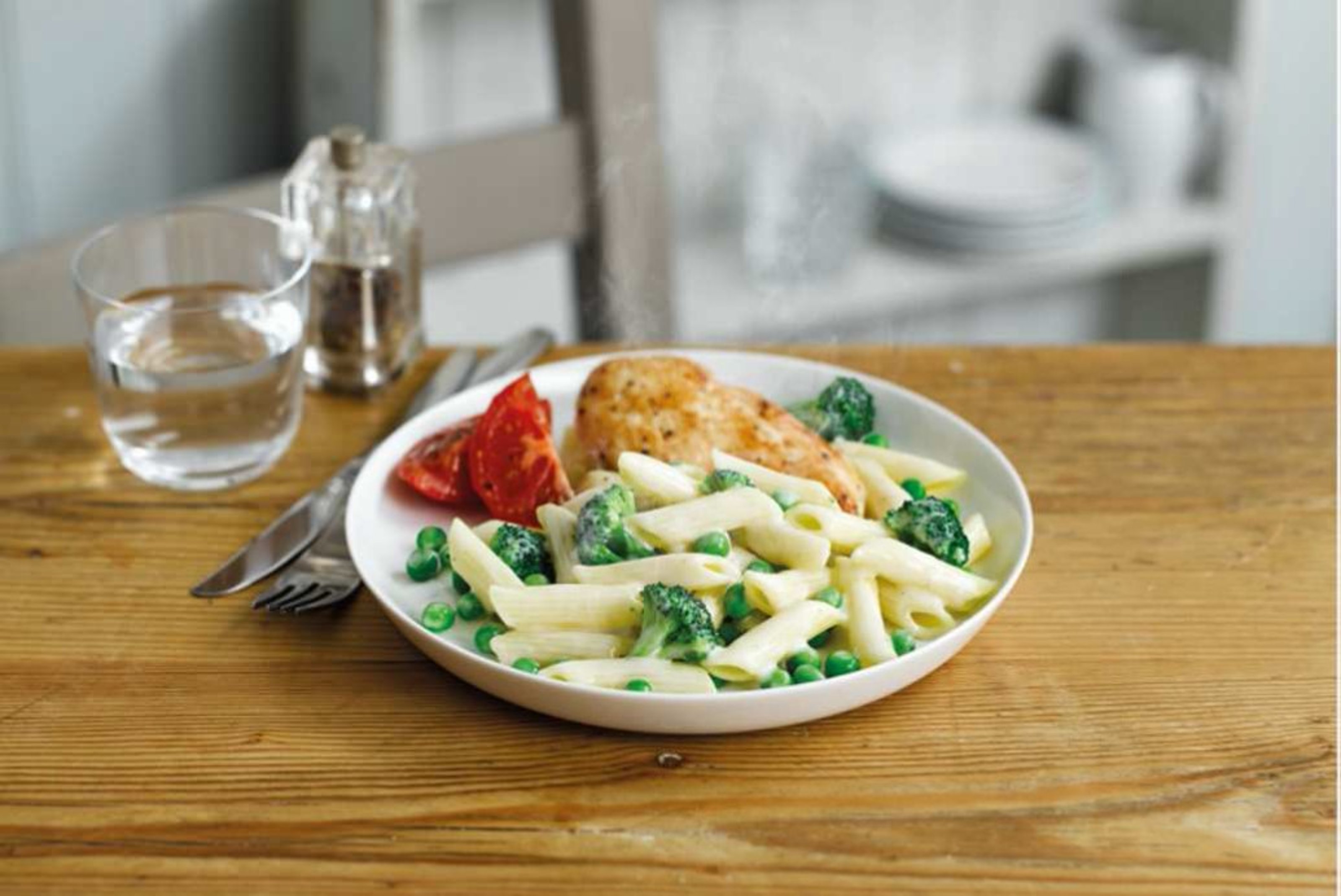 Plate of creamy penne with peas and broccoli, chicken and roasted tomato